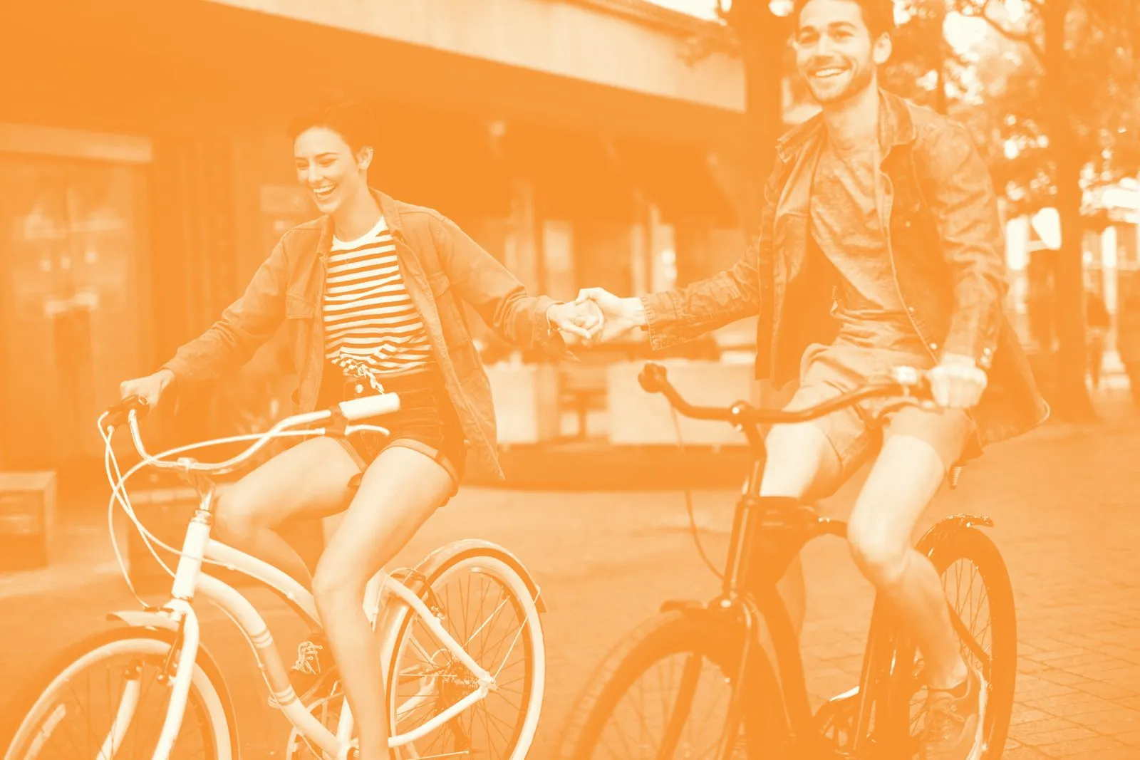 Pareja paseando en bicicleta, en duotono naranja